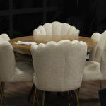 Okrągły stół z białymi krzesłami z oparciem w kształcie muszli